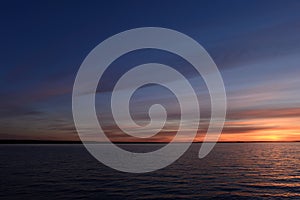 Blue sky in the twilight glow on the horizon over the water of the lake at sunset