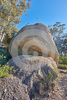 Blue sky, weathered rock and cracked stone from heat exposure and wind erosion along a countryside dirt path. Landscape