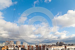 Blue sky with white clouds above roofs of apartment houses