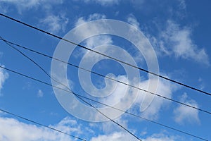 Blue sky with white clouds and electric transmision wires, in the daytime. photo