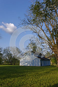 Blue Sky with white clouds in the Evening light above a Dutch Style Barn in a Paddock