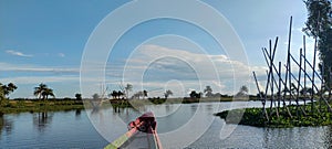 blue sky white clouds over the river with fishing boat village, fishing nets and bamboo sticks