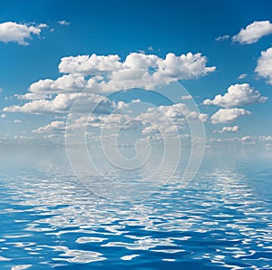 Blue sky with white clouds reflected in a water