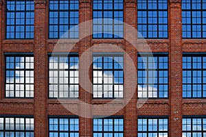 Blue sky and white clouds reflection in big glass windows in red brick walls