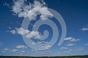 A blue sky with white fluffy clouds. Background, screensaver. Summer. Cloudy. Sunshine