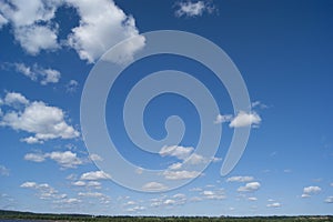 A blue sky with white fluffy clouds. Background, screensaver. Summer. Cloudy. Sunshine