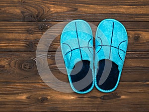 Blue Slippers on the dark brown wooden floor. The view from the top. Flat lay.