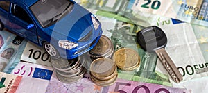 blue small toy car with key on background of euro paper bills