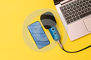 Blue and blue smartphone microphone near the laptop on a yellow background. The concept of workplace organization