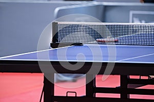 Blue and smooth surface table tennis table with tight black net to being prepared for practice and competition