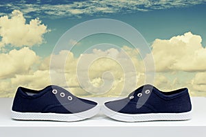 Blue sneakers on background cloudy sky