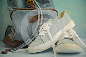 Blue sneakers with white laces and backpack on a light blue background.