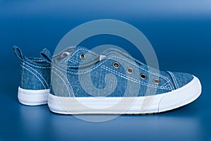 Blue sneakers with white soles without laces on a blue background