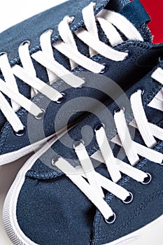 Blue sneakers with white toe and white laces on a white background with copy space