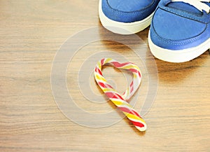 Blue sneakers. wooden background. Candy in the shape of a broken heart. It is expected that you will give up what you like and fro