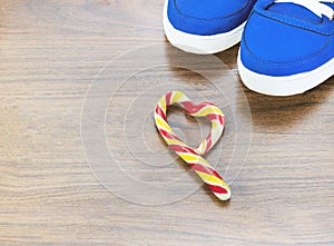 Blue sneakers. wooden background. Candy in the shape of a broken heart. It is expected that you will give up what you like and fro