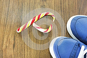 Blue sneakers. wooden background. Candy in the shape of a broken heart. It is expected that you will give up what you like and fro