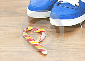 Blue sneakers. wooden background. Candy in the shape of a broken heart. It is expected that you will give up what you like and fro