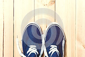 Blue sneakers on wooden background with copy space. Top view.