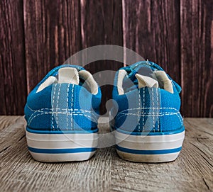 Blue sneakers on a wooden background. View from above....