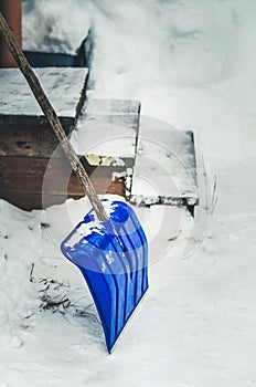 Blue snow shovel cleans sidewalks and stairs in winter season