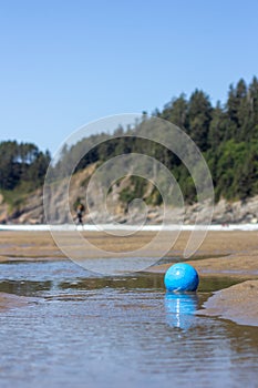 Blue soccer ball sits in one of the pools of the delta of a creek emptying into Smuggler Cove at Short Sand Beach on the Oregon