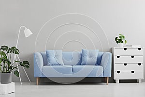 Blue sofa between white lamp and cabinet in grey living room int photo