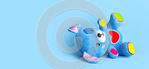 Blue soft children`s toy puppy with funny ears, multi-colored paws and red heart on blue background flat lay copy space