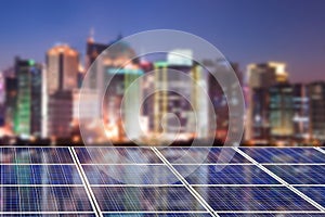 Blue solar cell panels, blurred city skyline illuminated at night