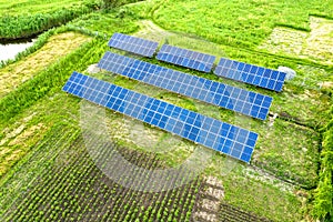 Blue solar photo voltaic panels mounted on metal frame standing on ground with green grass in field photo