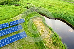 Blue solar photo voltaic panels mounted on metal frame standing on ground with green grass in field