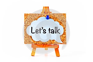 Blue speech bubble with phrase Let`s Talk on corkboard on wooden easel