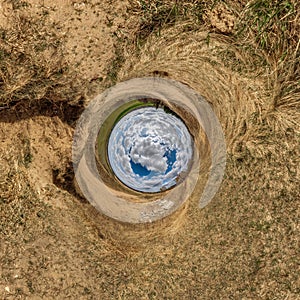 Blue sphere little planet inside yellow sand field background. curvature of space