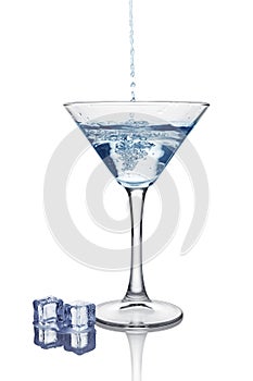 Blue splash in glass of white transparent alcoholic cocktail drink with ice cube