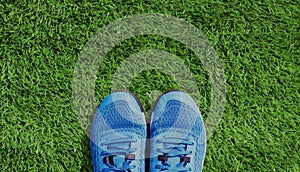Blue sports sneakers on a green grass background, blank copy space