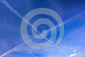 Blue spring sky with X-shaped traces of aircrafts