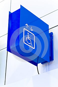 Blue square handicap sign with wheelchair elevator on w