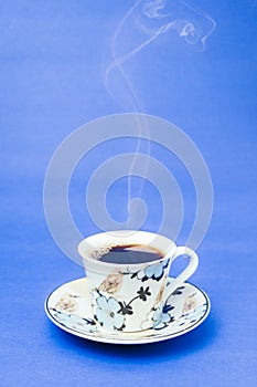Blue stamped mug with steaming coffee. Soft smoke. Blue background photo