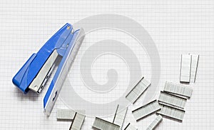 Blue Stapler and Piles of office Staples on Piece of Paper, Closeup