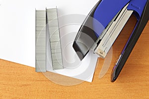 Blue stapler and staples with paper