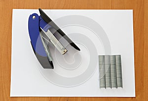 Blue stapler and staples with paper