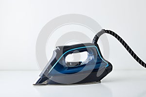 Blue steam iron isolated on white table side view