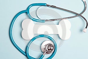 Blue stethoscope and symbolic bone on a blue background. Veterinary, animal care concept