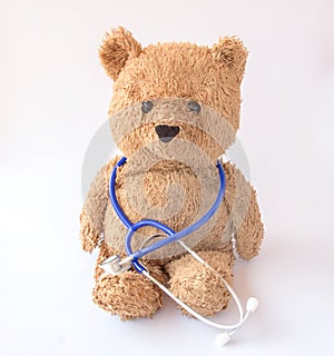 Blue stethoscope and teddy bear on white background
