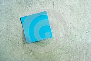 Blue sticky note on a plastered gray wall