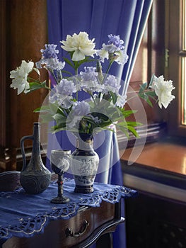 Blue still life with bouquet of peonies and irises