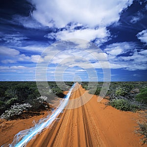 Blue streak of light on dirt road against cloudy sky