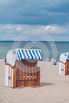 Blue striped roofed chairs on empty sandy beach in Travemunde. Blurred people in background