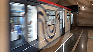 Blue subway train with people inside moving fast, view from metro station