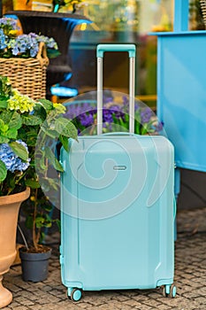A blue suitcase stands near the hotel door. Concept tourism, vacation, warm countries, tropics